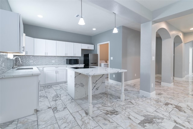 kitchen with sink, hanging light fixtures, a center island, washing machine and clothes dryer, and black appliances