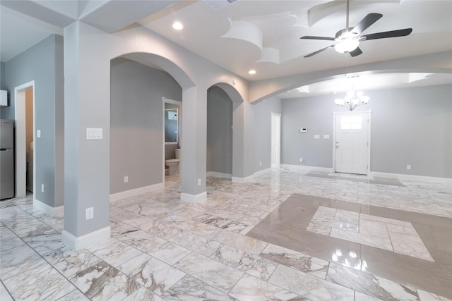 empty room featuring ceiling fan with notable chandelier