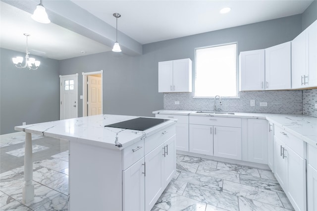 kitchen with a kitchen island, decorative light fixtures, sink, white cabinets, and backsplash