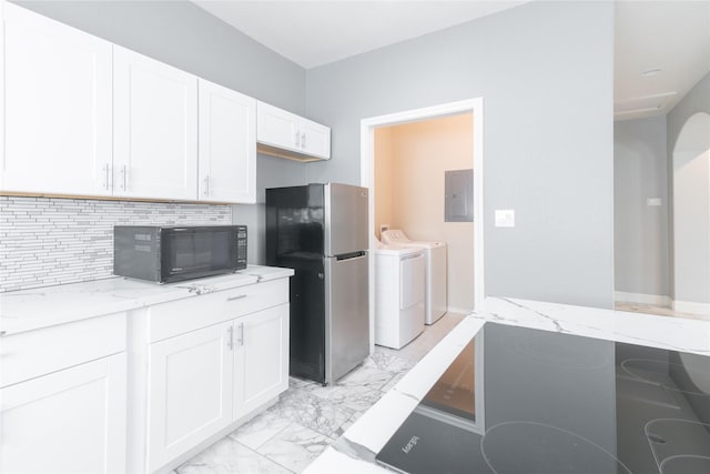 kitchen featuring washing machine and clothes dryer, tasteful backsplash, stainless steel refrigerator, light stone countertops, and white cabinets