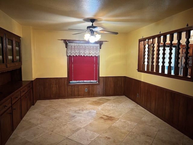 empty room featuring a textured ceiling, light tile patterned floors, and ceiling fan