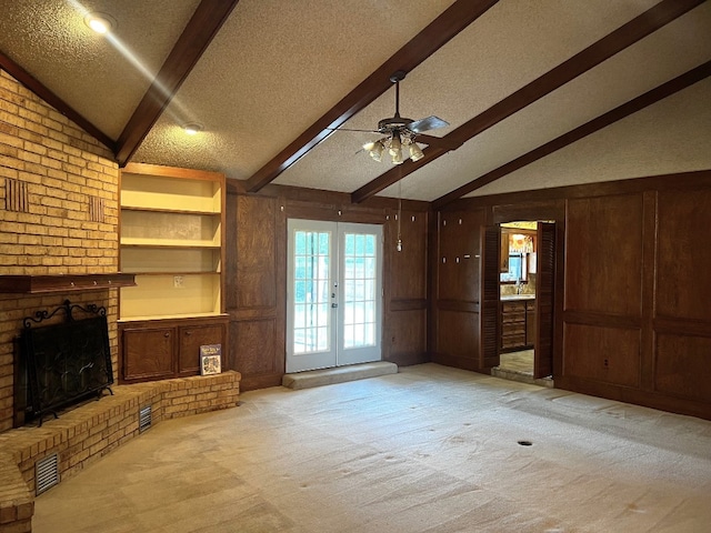 unfurnished living room featuring vaulted ceiling with beams, wooden walls, a textured ceiling, ceiling fan, and a brick fireplace