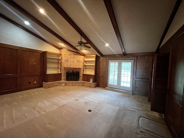 unfurnished living room featuring built in shelves, carpet floors, a fireplace, and lofted ceiling with beams