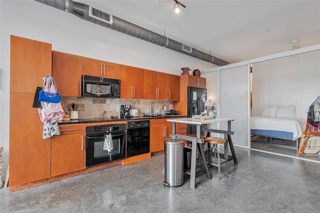 kitchen featuring tasteful backsplash, black appliances, sink, and concrete flooring