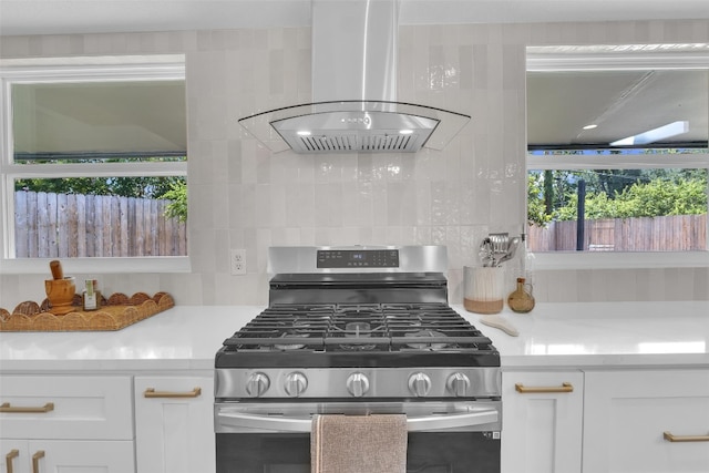 kitchen with gas stove, island exhaust hood, white cabinetry, and a healthy amount of sunlight