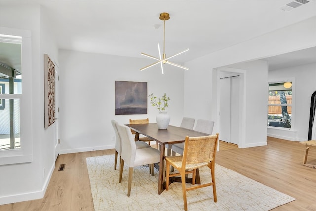 dining area with light wood-type flooring and a chandelier