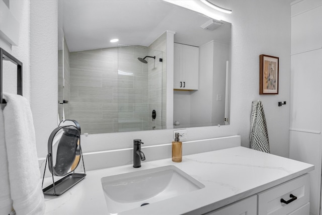 bathroom featuring tiled shower and vanity