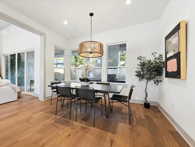 dining space with hardwood / wood-style flooring, a wealth of natural light, and a notable chandelier