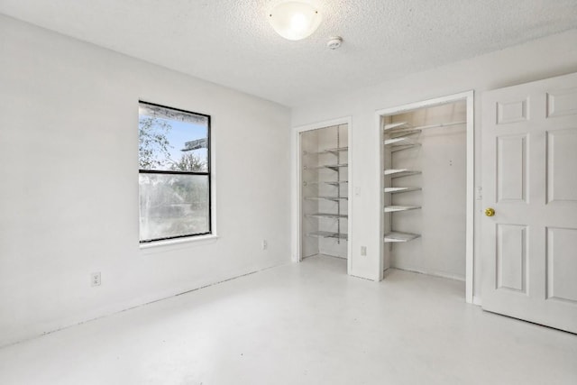 unfurnished bedroom featuring a spacious closet and a textured ceiling