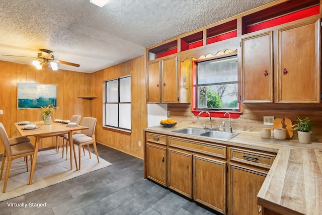 kitchen with a textured ceiling, wooden walls, and sink