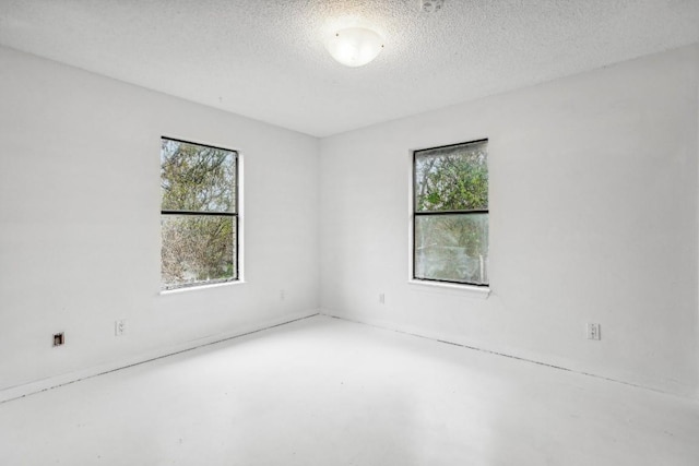 spare room with concrete flooring, a textured ceiling, and a wealth of natural light