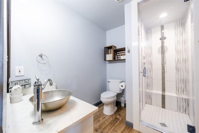 bathroom featuring wood-type flooring, vanity, toilet, and walk in shower