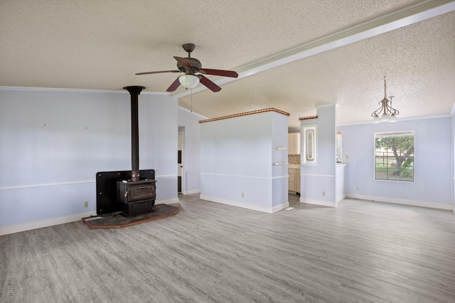 unfurnished living room with hardwood / wood-style floors, ornamental molding, a textured ceiling, vaulted ceiling, and a wood stove