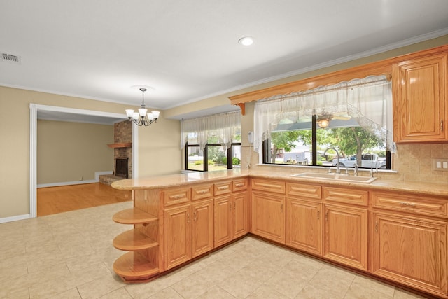 kitchen featuring a fireplace, sink, hanging light fixtures, kitchen peninsula, and crown molding