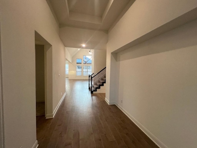 corridor with dark hardwood / wood-style floors and a tray ceiling