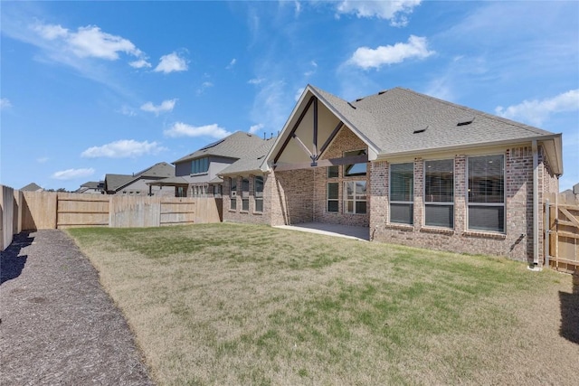 back of property featuring a patio, a fenced backyard, a yard, a shingled roof, and brick siding