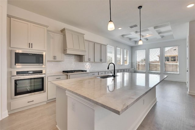 kitchen with coffered ceiling, gas stovetop, built in microwave, a sink, and stainless steel oven