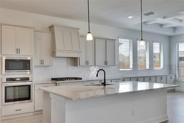 kitchen featuring premium range hood, a sink, cooktop, stainless steel oven, and built in microwave