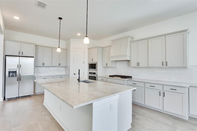 kitchen with visible vents, backsplash, stainless steel appliances, light wood finished floors, and custom exhaust hood