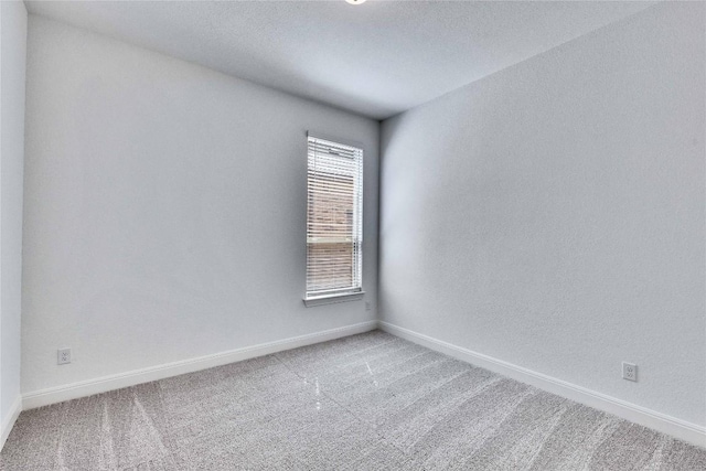 carpeted empty room featuring baseboards