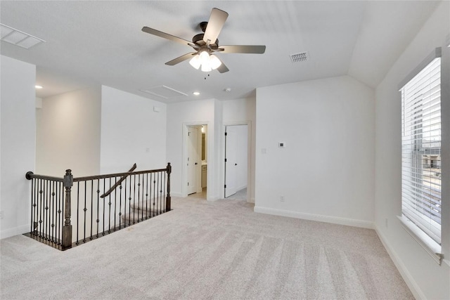 empty room with visible vents, light colored carpet, baseboards, and vaulted ceiling