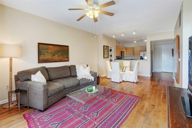 living room featuring ceiling fan, rail lighting, and light hardwood / wood-style floors