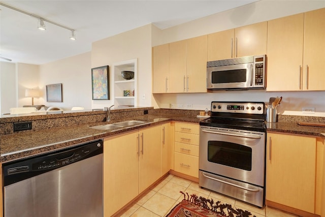 kitchen featuring sink, stainless steel appliances, light tile patterned flooring, dark stone counters, and light brown cabinets