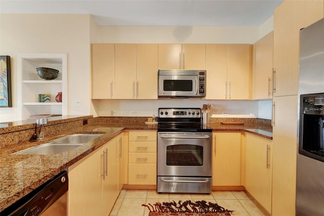 kitchen with light tile patterned flooring, sink, appliances with stainless steel finishes, kitchen peninsula, and stone counters