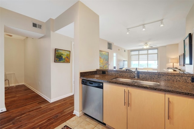 kitchen with sink, light wood-type flooring, light brown cabinets, stainless steel dishwasher, and dark stone counters