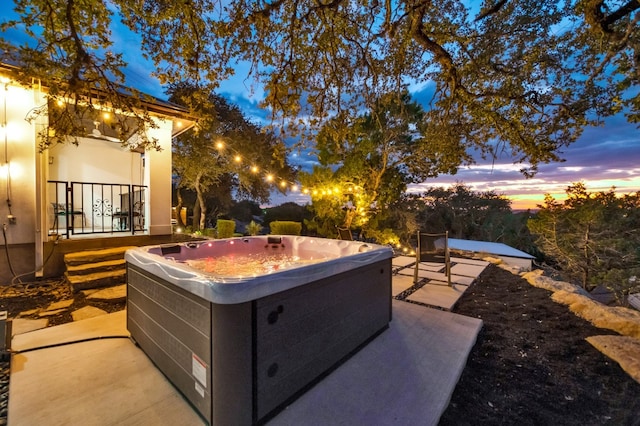 patio terrace at dusk featuring a hot tub