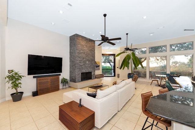 living room with light tile patterned flooring, a fireplace, ceiling fan, and a towering ceiling