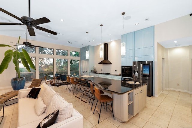 kitchen featuring a kitchen bar, pendant lighting, a kitchen island, black oven, and wall chimney exhaust hood