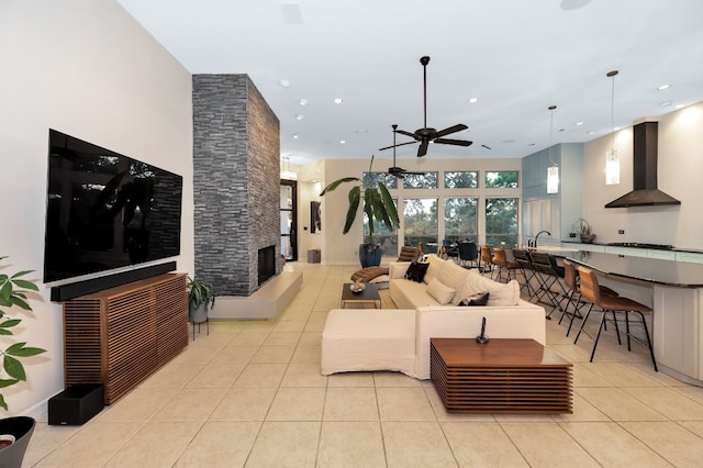 living room with sink, a fireplace, light tile patterned floors, a high ceiling, and ceiling fan