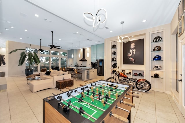 rec room with built in shelves, ceiling fan with notable chandelier, and light tile patterned floors