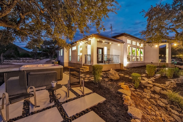 rear view of property with a patio and a hot tub