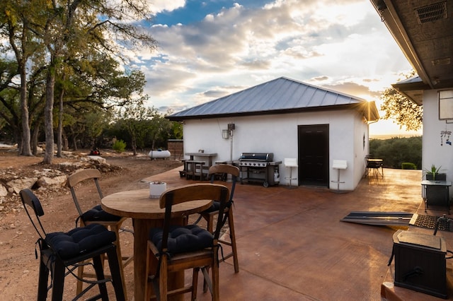 patio terrace at dusk featuring a grill