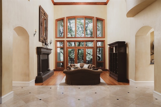 living room with ornamental molding, french doors, light wood-type flooring, and a high ceiling