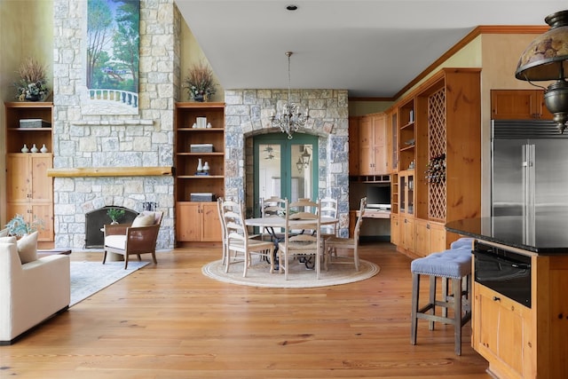 kitchen with light hardwood / wood-style flooring, french doors, hanging light fixtures, built in fridge, and a fireplace