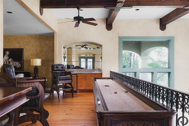 interior space featuring beamed ceiling, ceiling fan, and light wood-type flooring