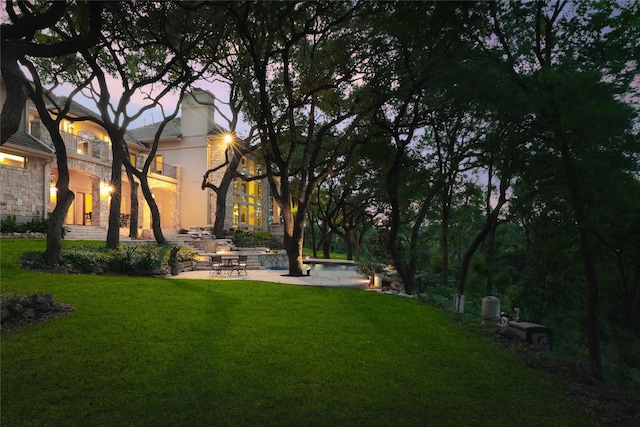 yard at dusk featuring a patio area