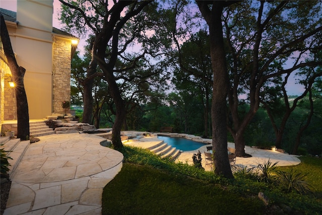 pool at dusk featuring a patio area