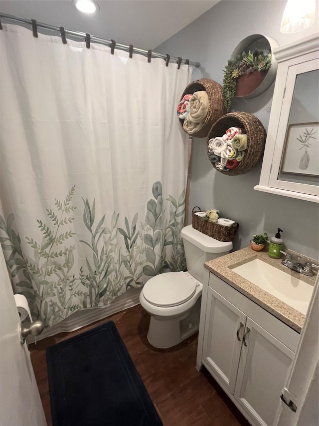 bathroom featuring wood-type flooring, toilet, and vanity