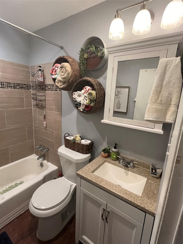 full bathroom with hardwood / wood-style floors, toilet, vanity, and tiled shower / bath