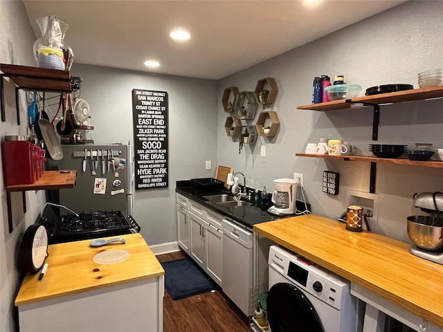 kitchen with washer / dryer, dark wood-type flooring, sink, stainless steel fridge, and white dishwasher