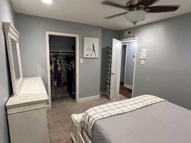 bedroom featuring light carpet, a closet, a spacious closet, and ceiling fan