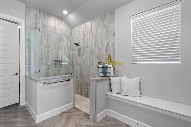 bathroom with tiled shower and vaulted ceiling