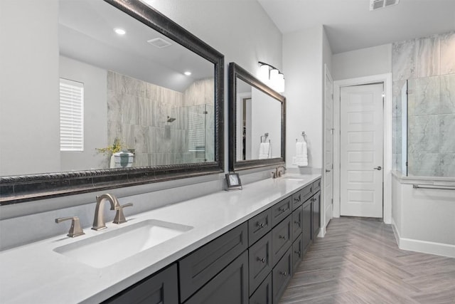 bathroom with vanity, a tile shower, and parquet flooring