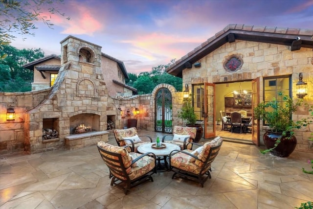 patio terrace at dusk featuring an outdoor stone fireplace