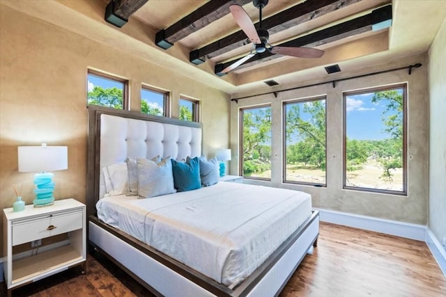 bedroom with ceiling fan, hardwood / wood-style floors, multiple windows, and beamed ceiling