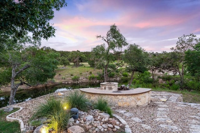 yard at dusk featuring a water view and an outdoor fire pit